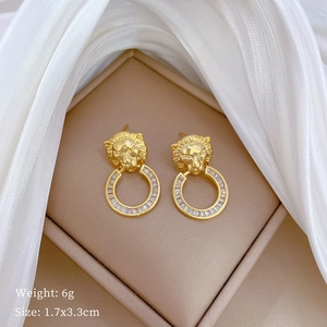 Detail of golden leopard head earrings with white zircon stones on a soft white fabric