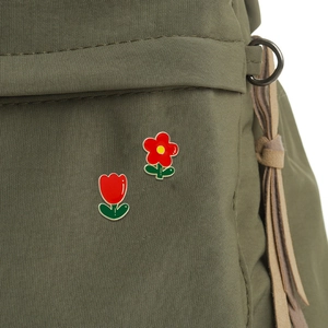 Lot de pins émaillés tulipe rouge et fleur sur un sac à dos en toile verte