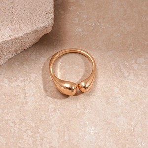 Close-up of golden teardrop open ring on natural sandstone with soft aesthetic lighting