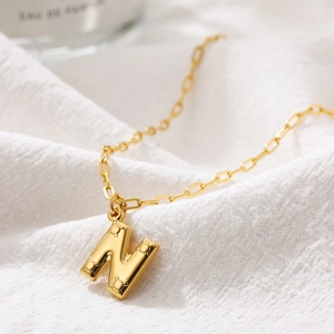 Detailed close-up of golden bubble initial N necklace with Mickey head dots and clip chain