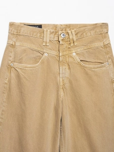 Detailansicht der gelbbraunen Denim-Taille mit Metallknopf und Gürtelschlaufen