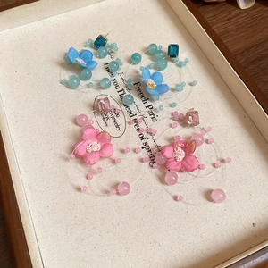 Close-up of floral tassel earrings with blue and pink fabric flowers and beaded strands