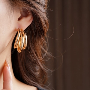 Gros plan de boucles d'oreilles multicouches dorées en forme de C portées par un mannequin
