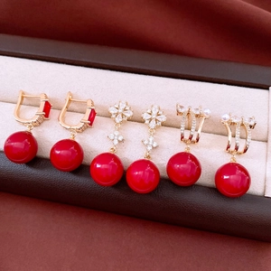 Macro detail of three elegant 18K gold plated red zircon earrings in a premium jewelry box