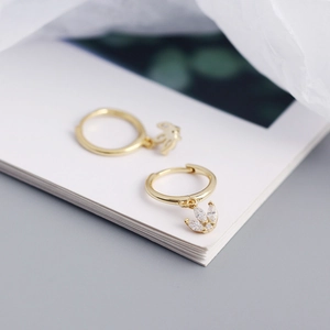 Close-up of gold S925 silver earrings featuring marquise zircon crown charms on open book