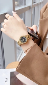 Détail d'une montre dorée pour femme avec cadran noir et bijoux élégants assortis sur le poignet