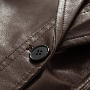 Détail d'une veste en cuir marron foncé montrant un bouton noir et une texture délavée