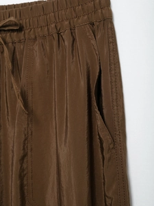 Detail of brown casual pants featuring an elastic drawstring waistband and side pocket