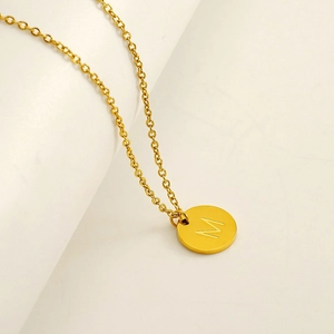 Vue macro d'un collier en acier inoxydable doré avec pendentif rond poli lettre M