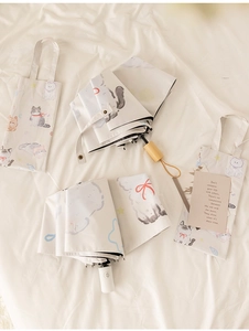 Detail of cute cat illustration folding umbrella with matching storage tote bag and wooden handle