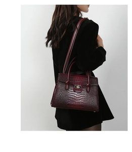 Close-up of burgundy crocodile pattern leather texture and metal buckle on handbag
