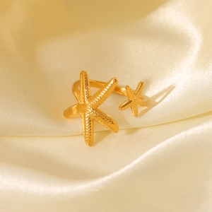 Detail of gold starfish open ring with dual starfish charms on champagne satin