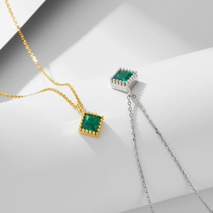 Minimalist square emerald zircon pendants in gold and silver finishes on textured fabric