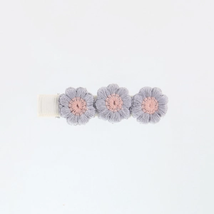 Detail showing three embroidered floral hair clips with purple petals and pink centers