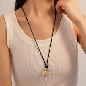 Minimalist gold organic pendant on black cord shown on white ribbed tank top