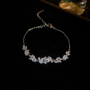 Macro detail of gold flower bracelet with marquise zircon leaves and lobster clasp