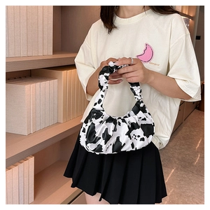 Detail of ruched handle on crescent cow print cloud bag styled with a casual outfit