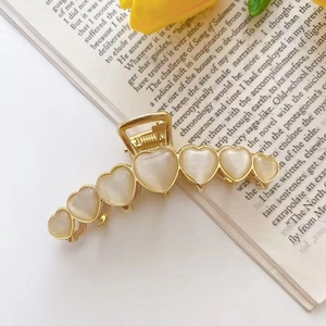 Detail of golden hair claw clip with heart-shaped opal stone on a vintage book