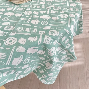Detail of mint green linen tablecloth featuring white kitchenware patterns and soft texture
