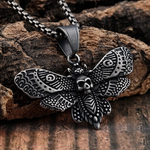 Pendentif papillon gothique avec crâne en argent vieilli sur fond de bois naturel