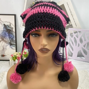 Detail of pink and black striped knit cat ear hat with pom-poms and thick yarn texture