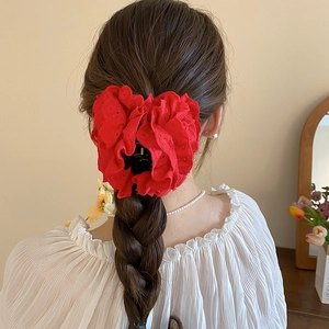 Détail de la pince à cheveux rose en dentelle rouge sur cheveux tressés avec broderie