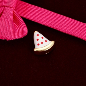 Macro view of a white pizza charm with red spots and gold trim for DIY jewelry