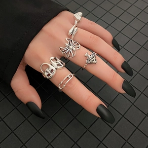 Gothic silver ring set featuring skull, butterfly, and mushroom designs on a hand