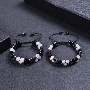 Detail of double-layer hand-woven rose quartz and obsidian beaded bracelets with adjustable cord