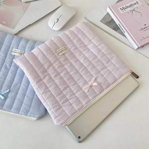 Quilted padded laptop sleeve with bow detail showing storage for a silver tablet