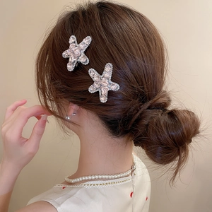 Close-up of sparkling star-shaped rhinestone hair clips worn by a model on side hair