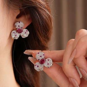 Close-up of vintage flower earrings with red gemstone and cubic zirconia on a model