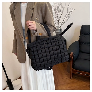 Close-up of black quilted puffer tote bag featuring crinkled texture and soft nylon fabric