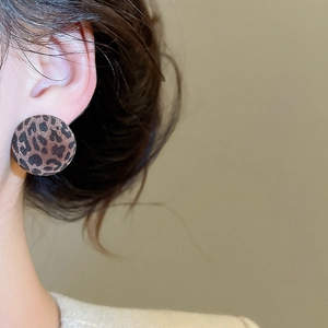 Detail of round leopard print earrings with a flocked texture worn by a model