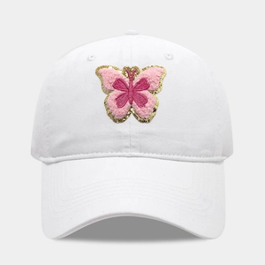 Détail de la broderie papillon en peluche rose avec fil doré sur casquette en coton blanc
