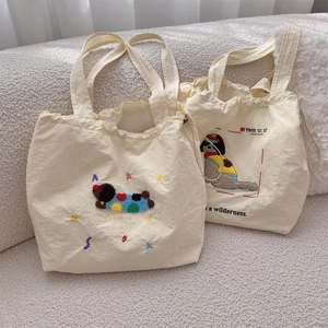 Close-up of beige canvas tote bag featuring cute cartoon dog embroidery and drawstring