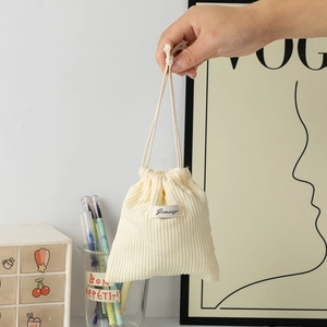 Detail of soft cream corduroy drawstring makeup bag with textured fabric and label
