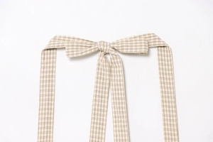 Detail of checkered fabric belt with beige and brown plaid pattern and woven texture