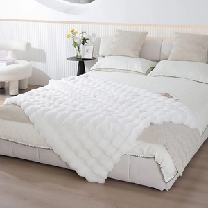 Detail of white faux rabbit fur blanket featuring soft wave texture on a modern bed