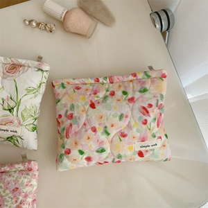 Quilted floral makeup bag with simple wish label on a warm beige table with accessories