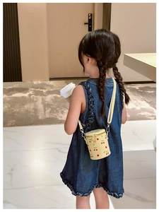 Girl wearing a light yellow cherry print bucket bag with adjustable shoulder strap detail