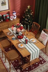 Detailed close-up of a festive Christmas table runner with green tassels on a wooden table