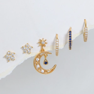 Star and moon gold earring set with blue and white zircons on white artistic paper