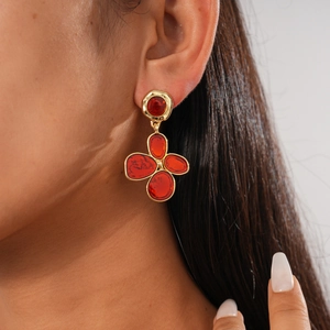 Close-up of vintage gold-trimmed red flower earring worn by a model for elegant styling