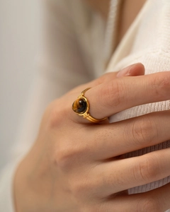 Macro shot of gold vintage oval tiger eye stone ring on minimalist knit fabric background