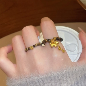 Detailed shot of tiger eye bead elastic ring with golden horse and coin charms