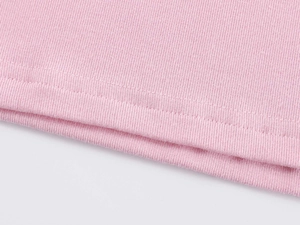 Close-up of pink knit t-shirt fabric showing detailed ribbed texture and double stitching