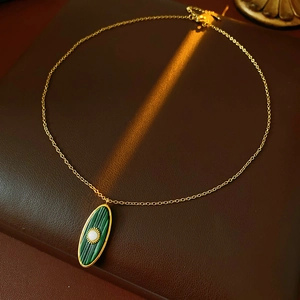 Detail of vintage gold sun oval necklace with green malachite stone on leather