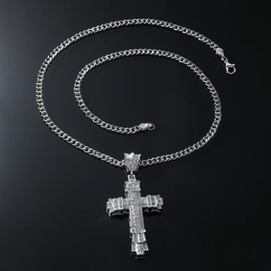Macro detail of silver tone cross pendant with rhinestones on a chunky cuban chain
