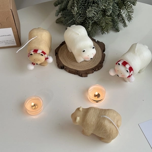 Detail of polar bear candles with red scarves on a rustic wooden tray with pine branches